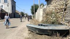 A small boat rests by the side of a road in Kherson, Ukraine, as residents carry bottled water