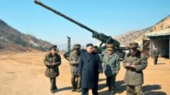 North Korean leader Kim Jong-Un stands in front of a long-range artillery with other officials