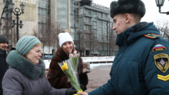 Сотрудник МЧС России дарит женщине тюльпаны
