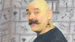Фотография лысого мужчины на фоне разрисованной тюремной стены