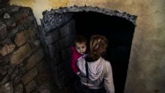 Женщина с ребенком спускается в подвал во время обстрела в Шуше, Нагорный Карабах, 8 октября