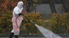 A municipal worker wearing protective equipment sprays disinfectant on a sidewalk in Moscow