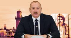 Президент Азербайджана за столом на фоне Баку и журналистки за решеткой