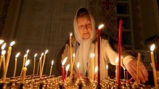 Woman lights candle at Christian Orthodox Church for Christmas