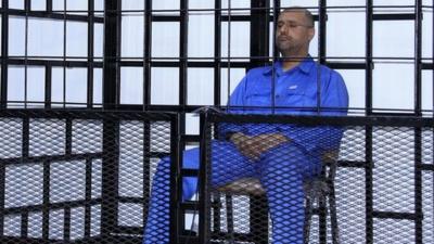 File image from 2014 - Saif al-Islam Gaddafi, son of late Libyan leader Muammar Gaddafi, attends a hearing behind bars in a courtroom in Zintan