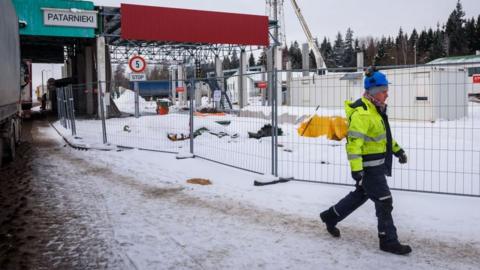 A worker walks near a construction site at the Latvian-Belarusian border