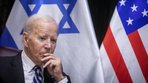 Joe Biden in front of American and Israeli flags