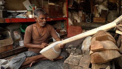 An artisan working on a sitar