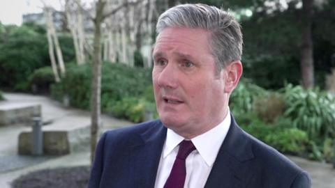 Keir Starmer head and shoulders portrait wearing suit and tie outside