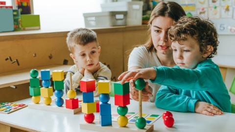 Female teacher helping little boy sort the cubes by colour