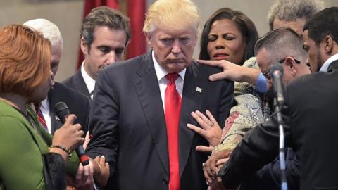 People lays hands and pray for Trump during a visit to a revival church in Ohio
