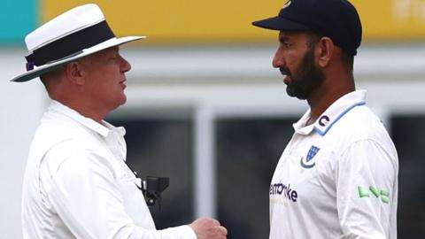 Match umpire Ben Debenham speaks with Sussex captain Cheteshwar Pujara during their match against Leicestershire