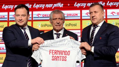 Fernando Santos holding up a Poland shirt