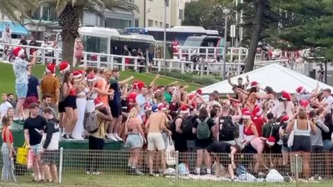 The crowd of backpackers, many wearing Santa hats, at Bronte Beach on Christmas Day