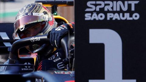 Red Bull's Max Verstappen gets out of his car after winning the Sao Paulo Grand Prix sprint race, with a 'Sprint 1' sign in the foreground
