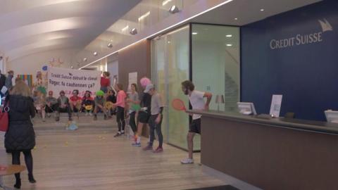 Activists playing tennis inside Credit Suisse offices