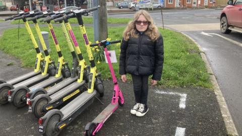 Ella Wakley showing height comparison with rental electric scooters