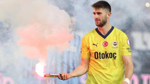 Ismail Yuksek of Fenerbahce holds an object thrown from the stands