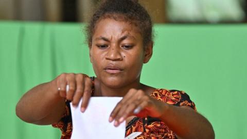 A woman drops her ballot paper into the box during the general elections in Honiara, capital city of the Solomon Islands, on April 17, 2024