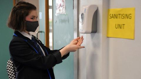 Secondary school pupil uses hand sanitiser