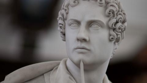 A close-up of a statue of Lord Byron, holding a pencil to his chin, Wren Library, Trinity College