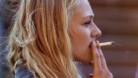Blonde woman smoking cigarette - stock photo