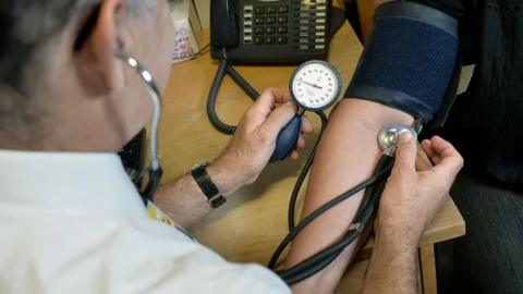 A GP checking someone's blood pressure