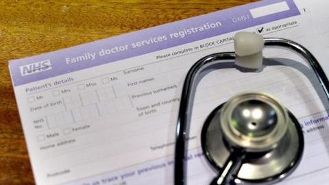 File image of a stethoscope lying over an NHS GP's new patient form