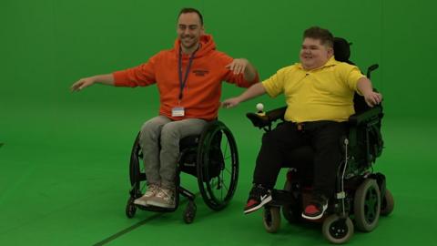 Seth and another wheelchair user trying out Just Dance game with green screen behind