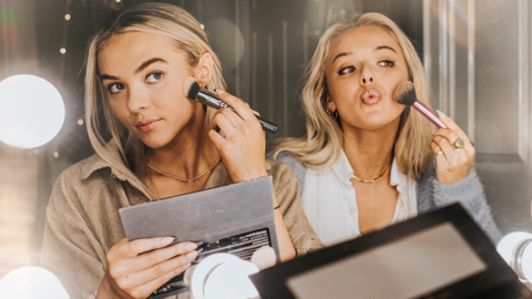 Two young women putting on make-up