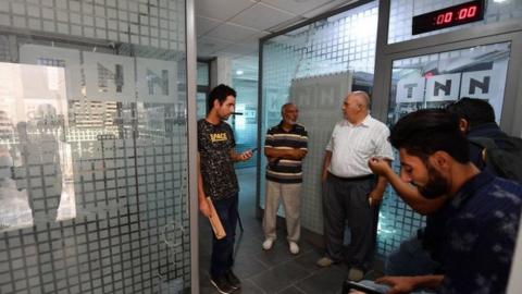 Employees gather inside the building housing the Zitouna TV channel gather on October 6, 2021, after Tunisian authorities seized broadcasting equipment