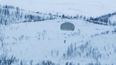 US Army paratrooper parachuting onto Norway landscape
