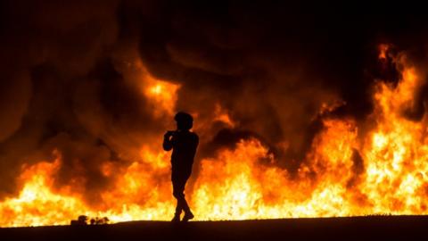 An Israeli citizen standing in front of a fire