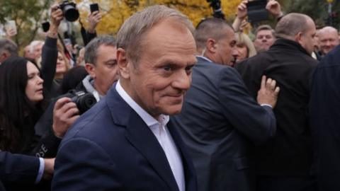 Donald Tusk leaves a polling station surrounded by crowds held back by security on 15 October 2023 in Warsaw, Poland.
