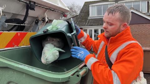 Council worker puts contents of food waste bin into the council truck