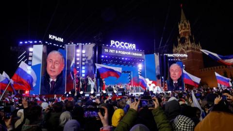 Russian President Vladimir Putin is seen on screens at a concert in Moscow