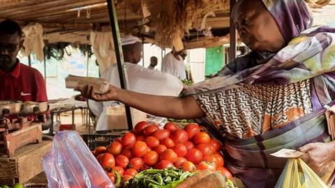 A woman buys fresh groceries from a market.
