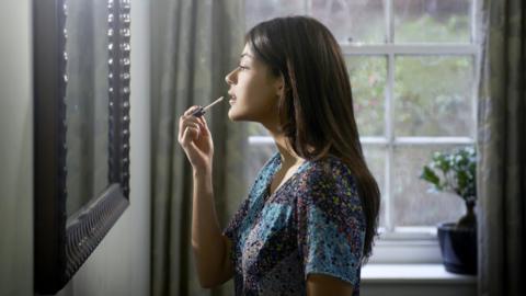 Woman applying lipstick in mirror