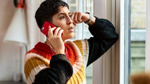 A woman at home on hold on her mobile phone