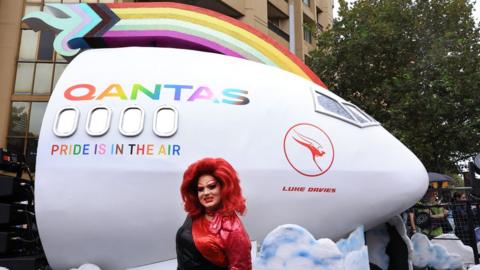 A Parade goer stands in front of the QANTAS float ahead of the Sydney Gay & Lesbian Mardi Gras Parade