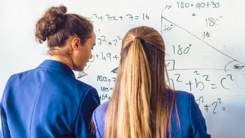 Two girls looking at maths equations