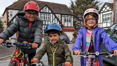 Kamran, Harris and Eve Javaid wearing helmets while riding their bikes.