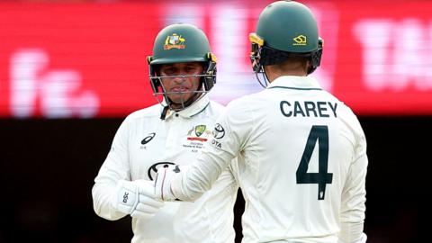 Usman Khawaja and Alex Carey touching gloves after reaching their fifty partnership