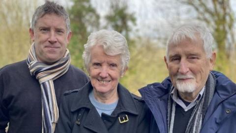 Two men and a woman look at the camera, smiling