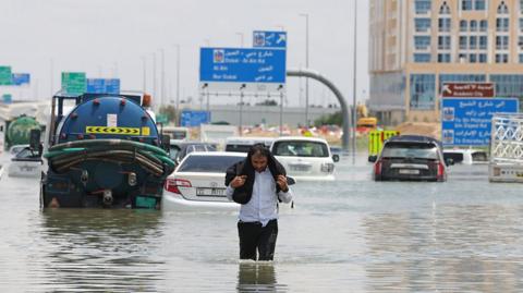 Man walks through floodwater in Dubai