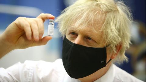 Boris Johnson with a vaccine vial