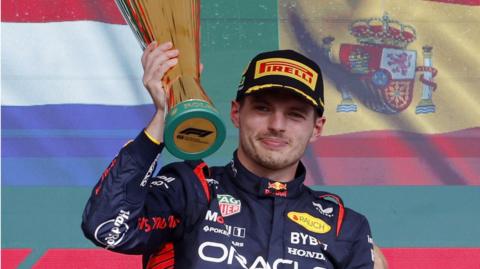 Max Verstappen holds aloft his winner's trophy on the podium after the Sao Paulo Grand Prix