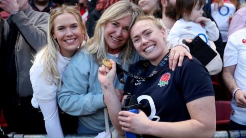 Rosie Galligan of England poses for a photograph with her Guinness 0.0 Player of the Match medal and members of the crowd after the match between England and Wales at Ashton Gate