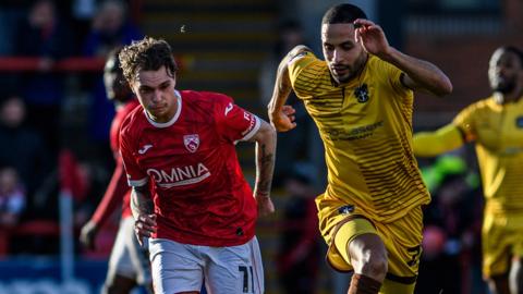 Julian Larsson of Morecambe and Joe Kizzi of Sutton United are chasing the ball during the League Two match between Morecambe and Sutton United