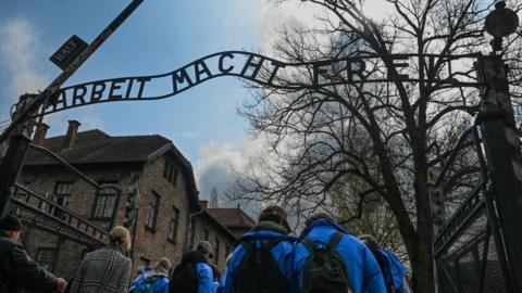 Participants seen at the Gate to Auschwitz I with its 'Arbeit macht frei' sign (English: 'work sets you free'), on April 18, 2023